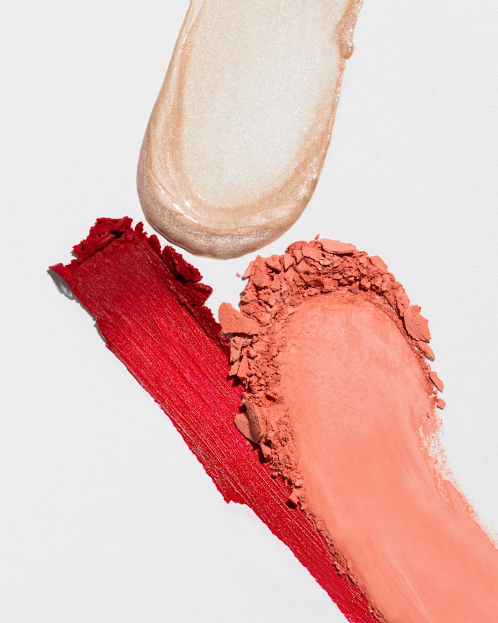 Close-up of vibrant makeup smears and swatches on a white background, showcasing texture and color.