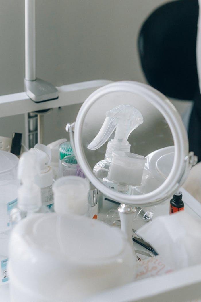 Close-up of cosmetic tools and products on a vanity, including a mirror and spray bottle.
