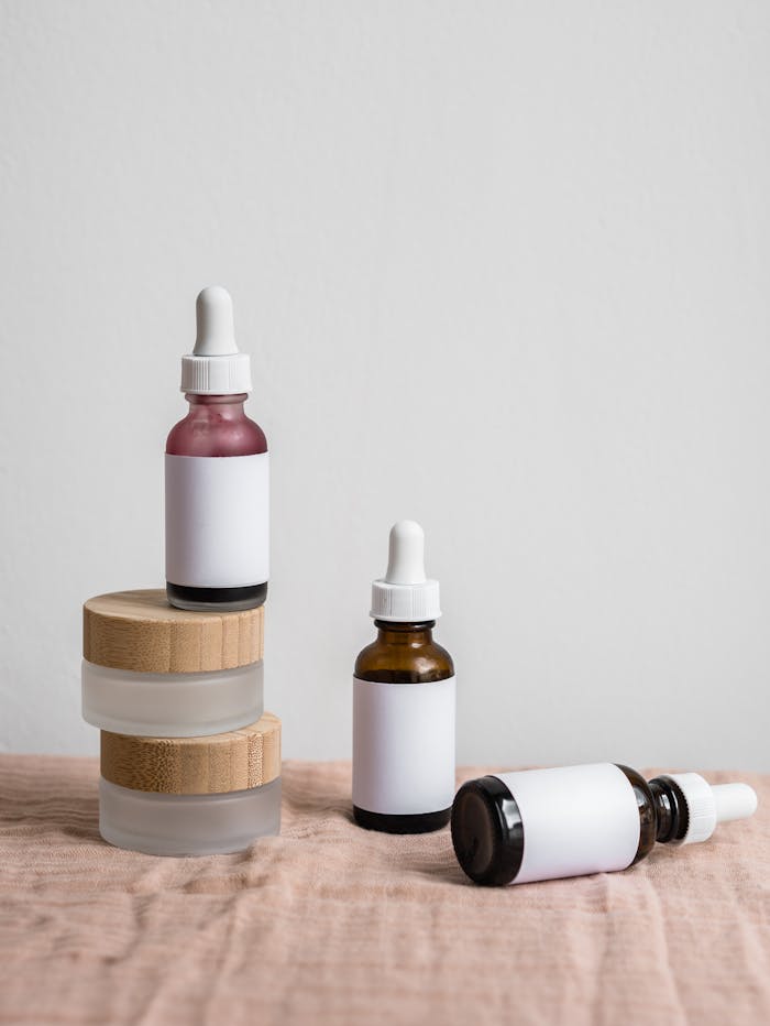 A minimalist skincare display featuring dropper bottles on a soft surface with wooden accents.