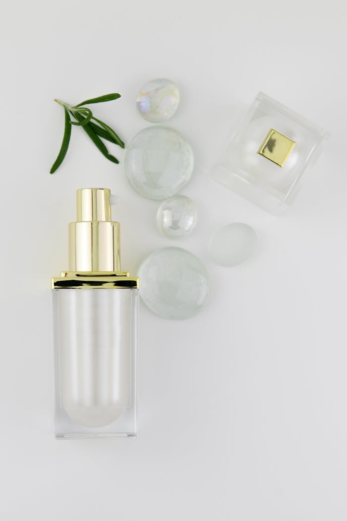 ours-journey A minimalist aesthetic featuring a perfume bottle with glass lid, crystals, and leaves on a white background.